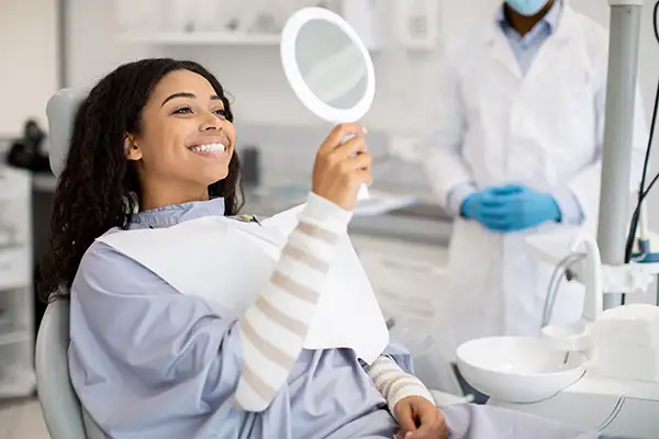 Black woman holding hand held mirror at Robert F. Walker Jr. DDS in Chandler, AZ