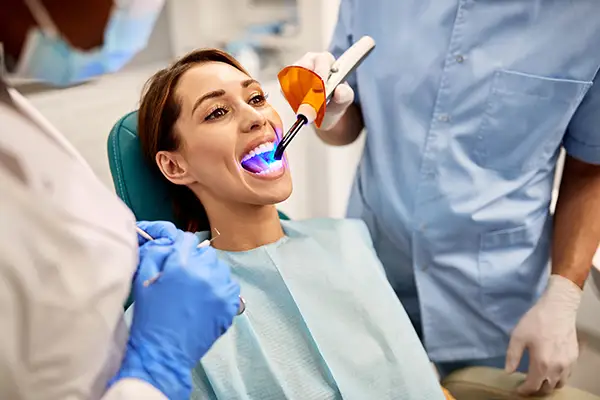 Dentist and assistant performing a dental bonding procedure on a patient