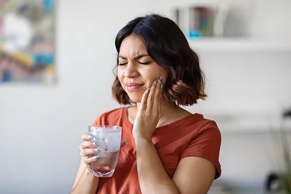 Young woman rubbing her jaw and wincing in pain.